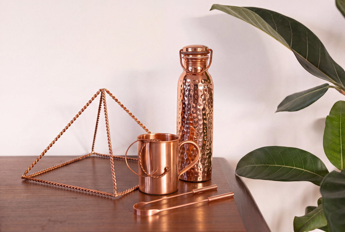 Copper tongue scraper, pyramid, mug and water bottle from the Kopero collection together on a wooden table