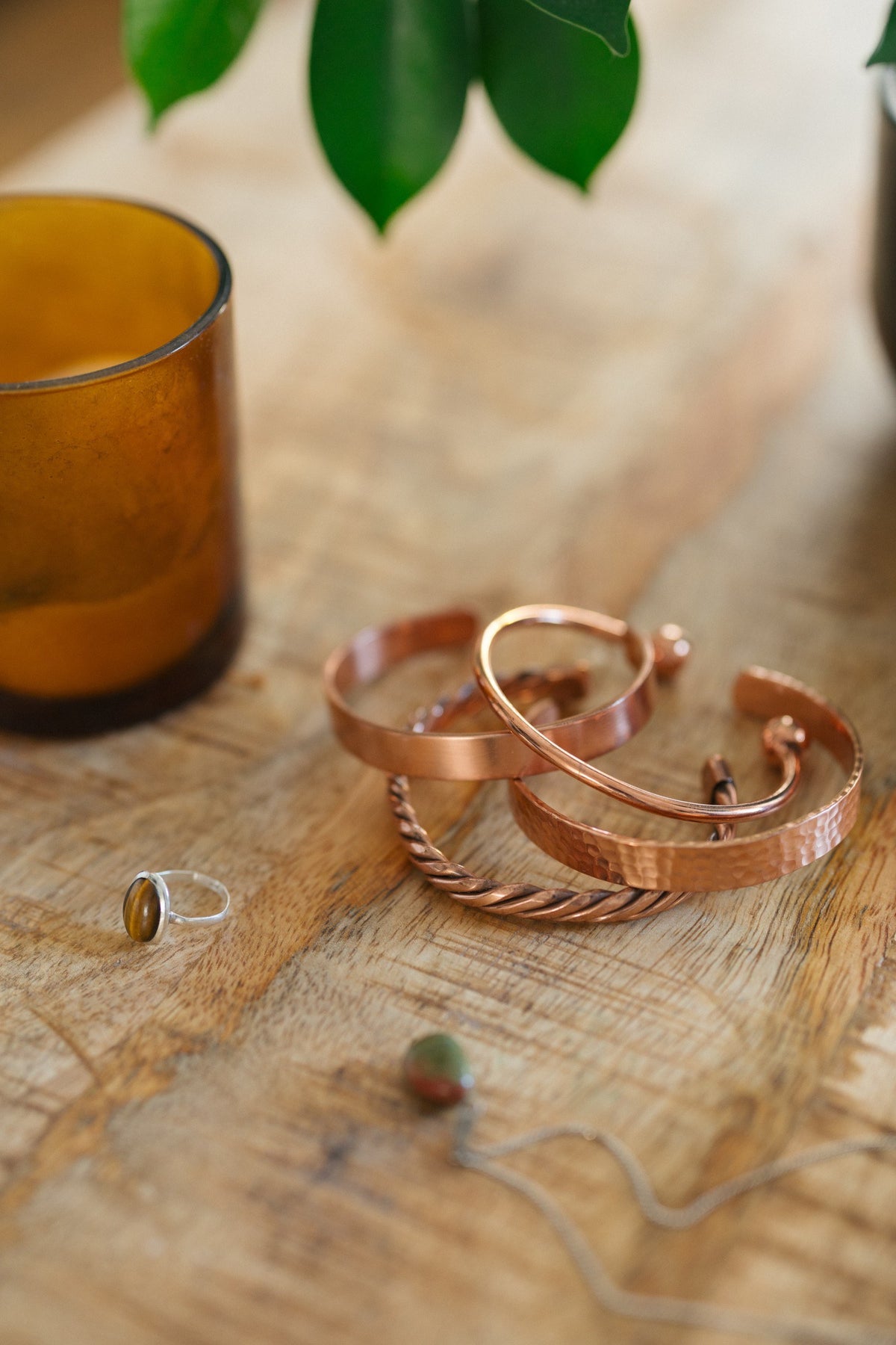 Kopero Copper Bracelet, all four versions together on a wooden table with a candle and a ring