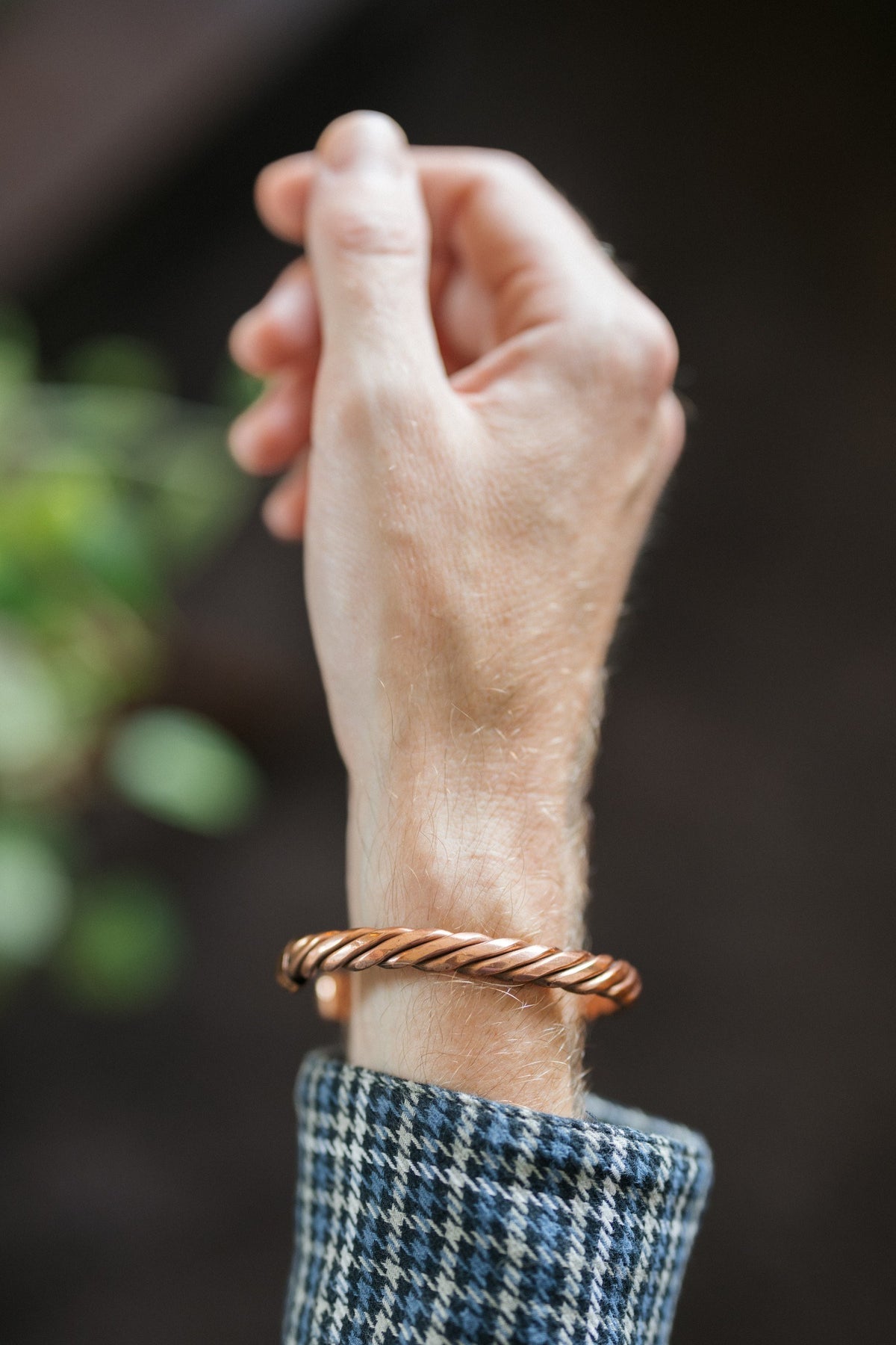 Kopero Copper Bracelet Twisted, on the wrist, with the hand raised against a dark background