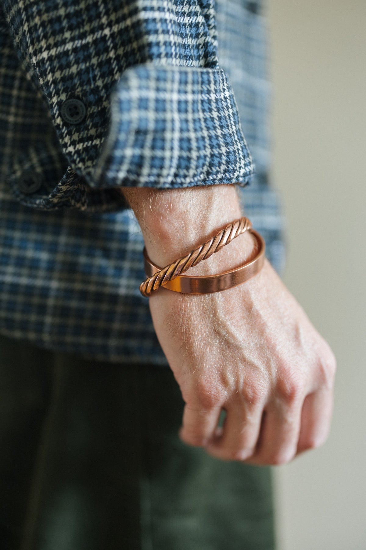 Kopero Copper Bracelet Twisted, on the wrist over a checked shirt sleeve, together with a smooth bracelet