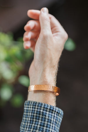 Kopero Copper Bracelet Hammered, on the wrist, with the hand raised against a dark background