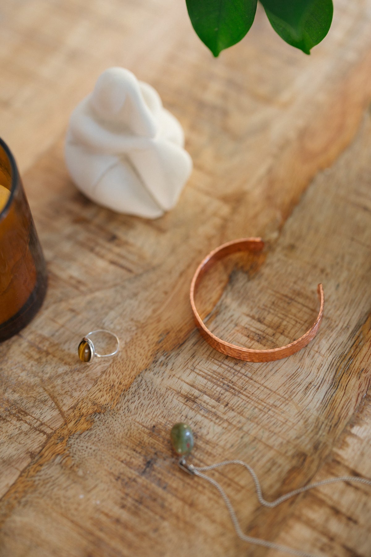 Kopero Copper Bracelet Hammered, on a wooden table next to a figurine and a ring