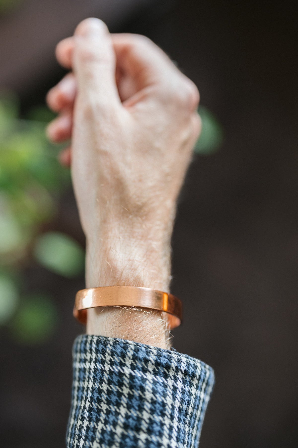 Kopero Copper Bracelet Smooth, on the wrist, with the hand raised against a dark background