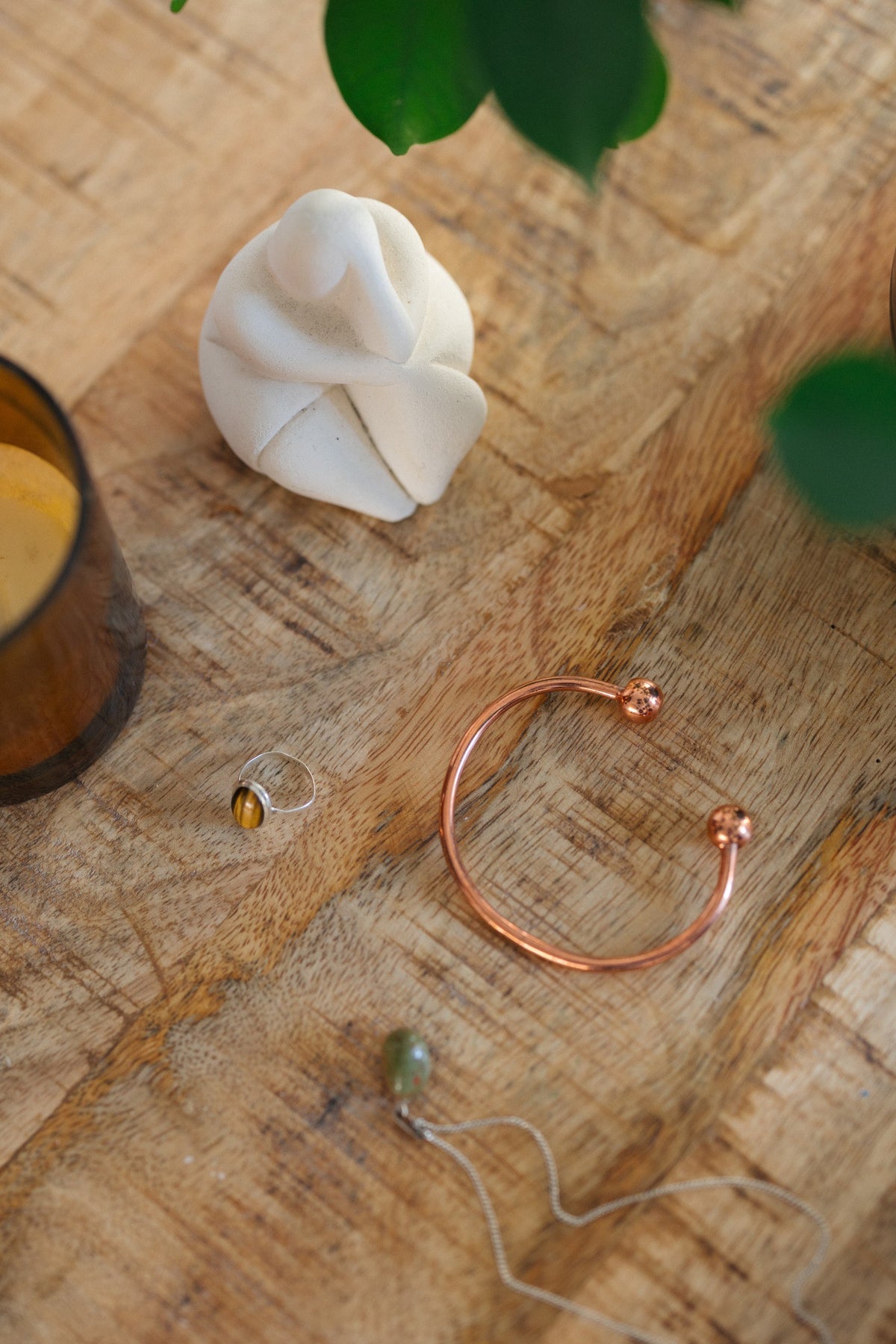 Kopero Copper Bracelet Round, on a wooden table next to a figurine and a ring