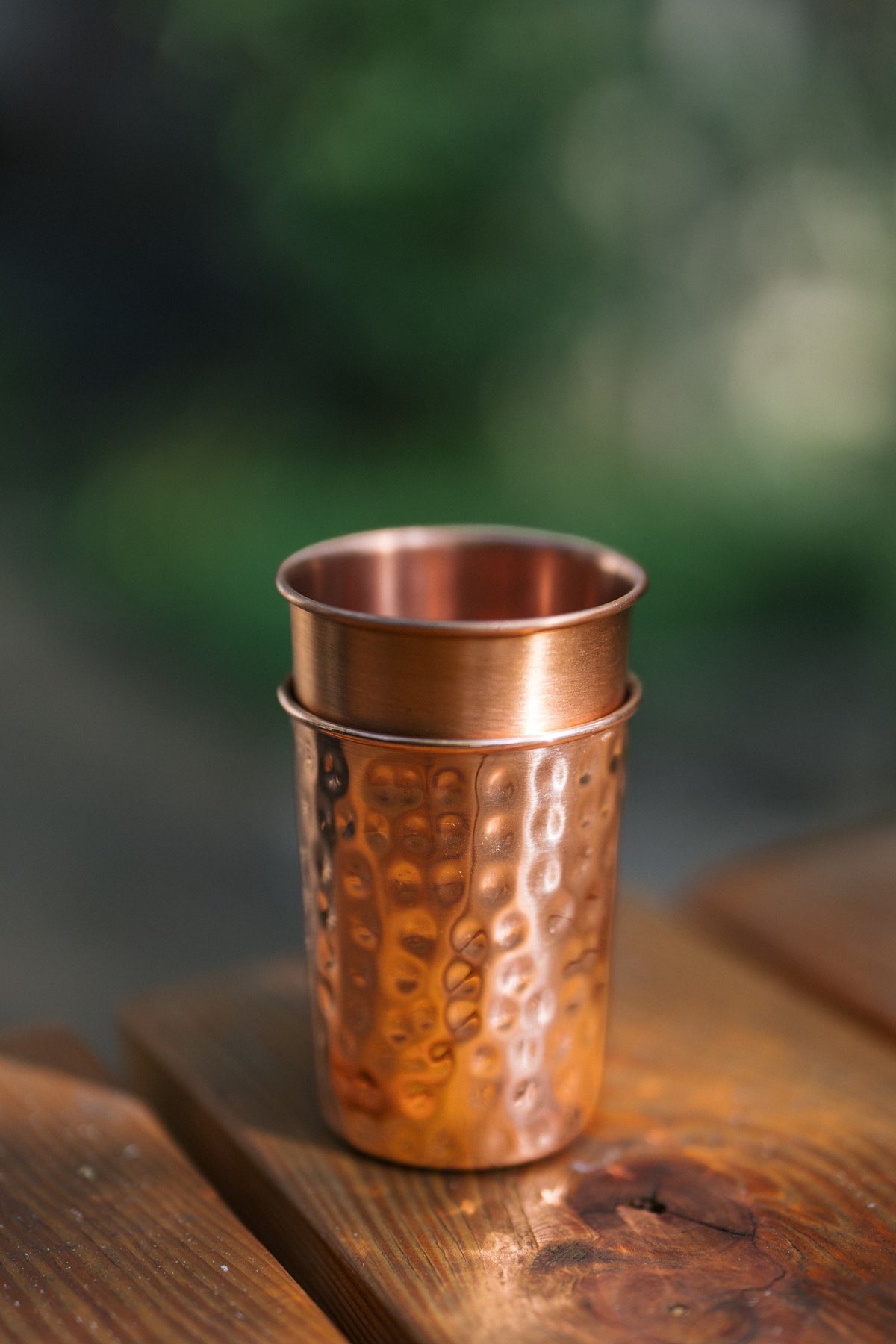Kopero Copper Cup, a smooth and a hammered cup stacked on top of each other on a wooden table