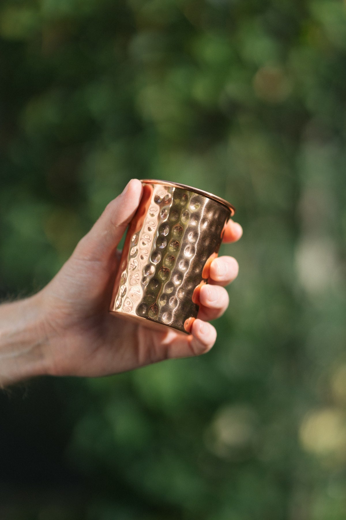 Kopero Copper Cup Hammered, in a hand against a green background