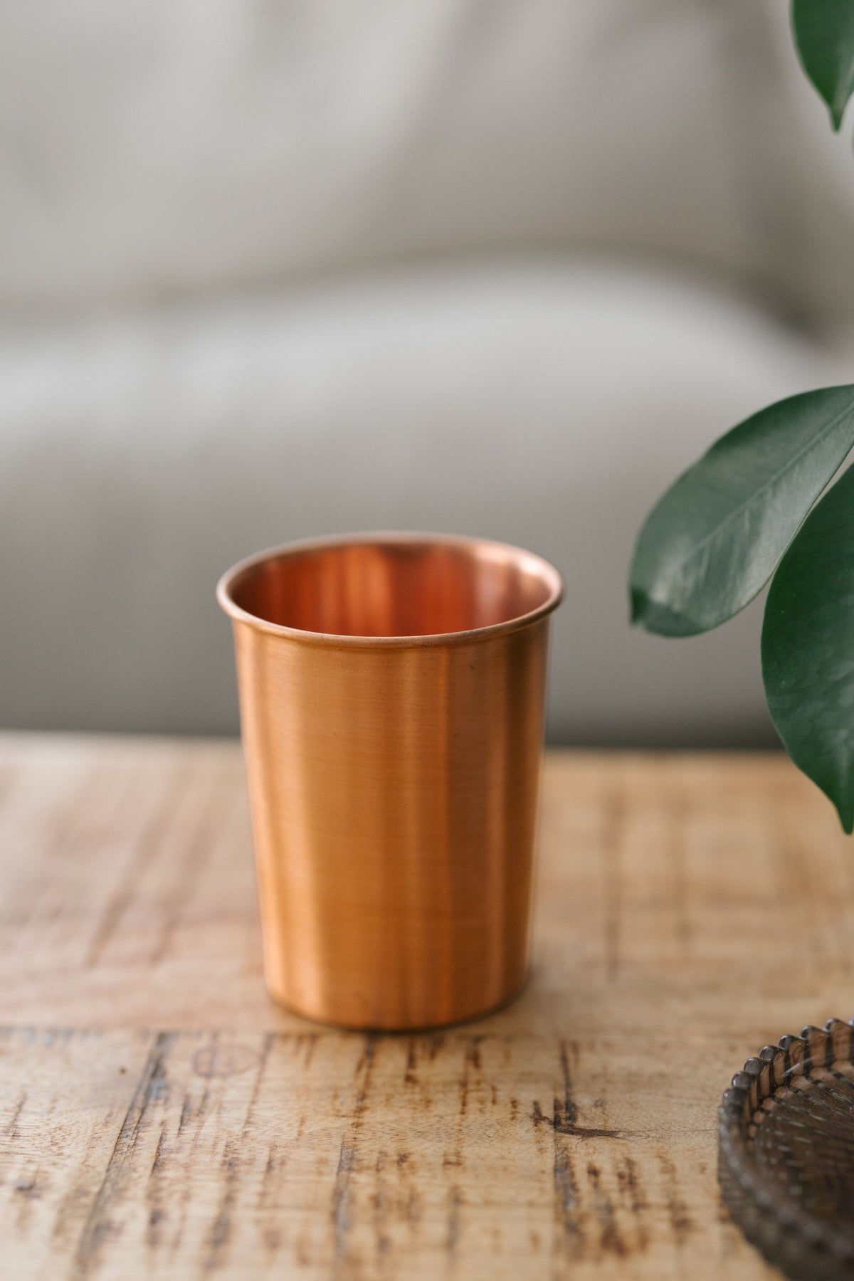 Kopero Copper Cup Smooth, on a wooden table in front of a sofa