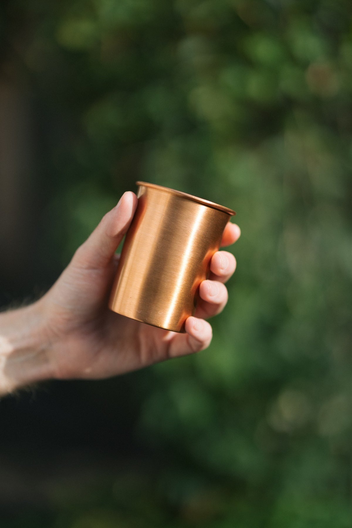 Kopero Copper Cup Smooth, in a hand against a green background