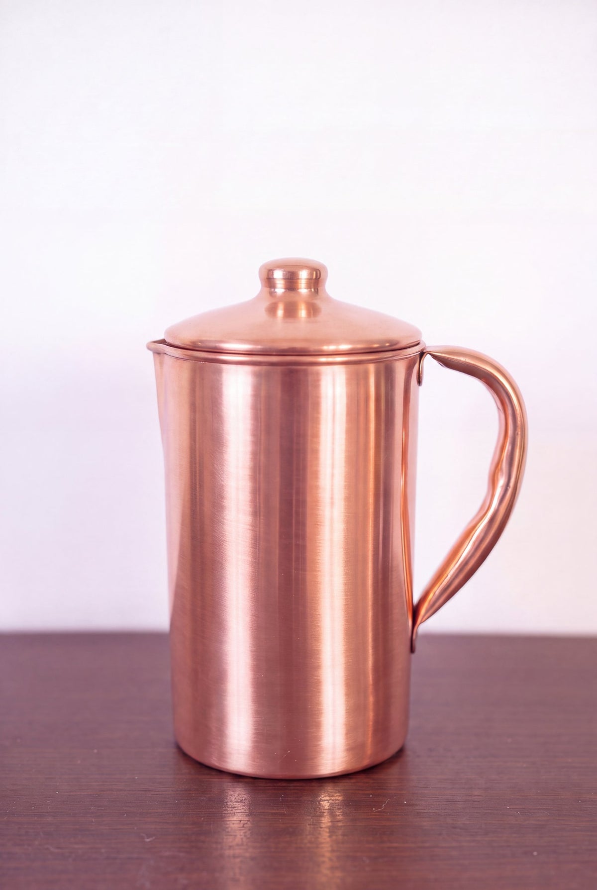 Kopero Copper Jug Smooth 1.4 liter with lid on a wooden table