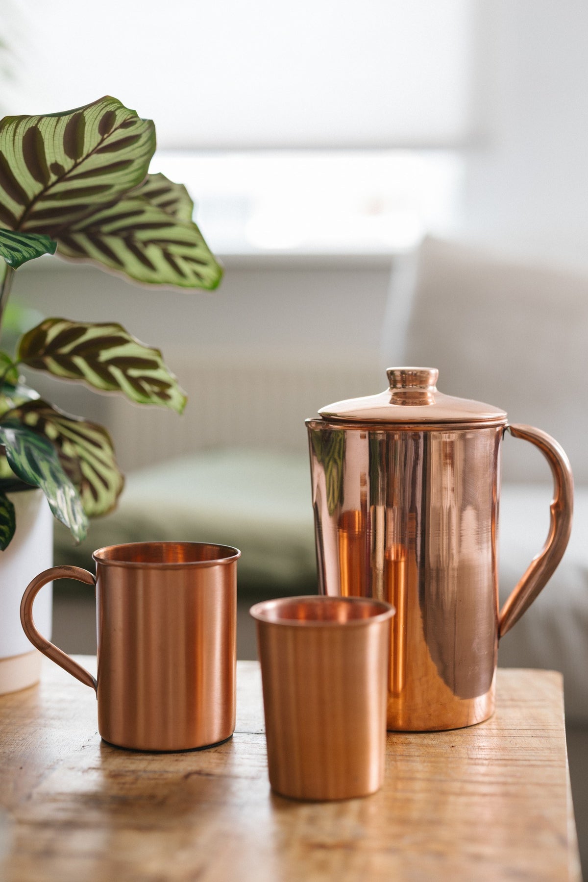 Kopero Copper Jug Smooth, with a mug and a cup on a wooden table