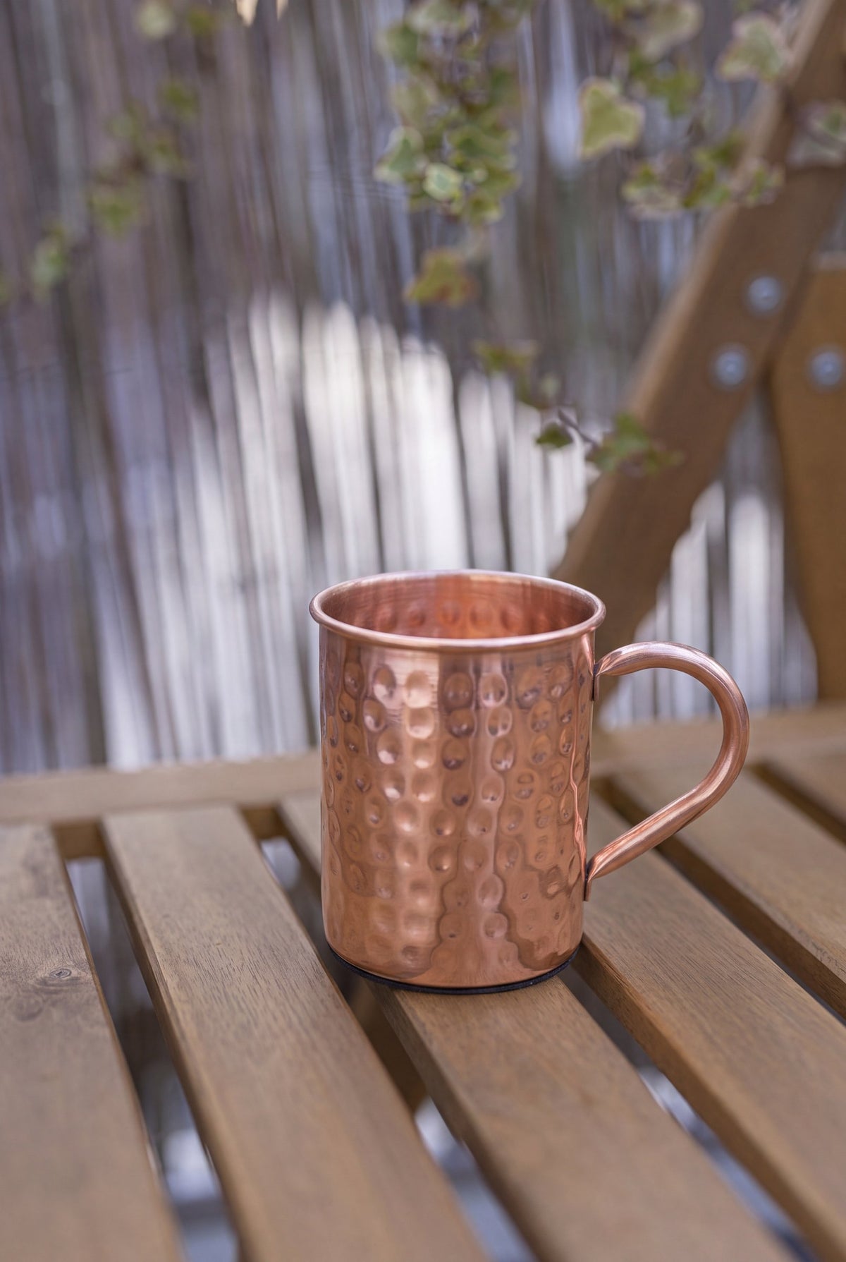 Kopero Copper Mug Hammered 400 ml on a wooden garden bench