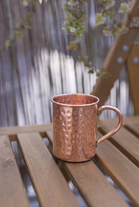 Kopero Copper Mug Hammered 400 ml on a wooden garden bench