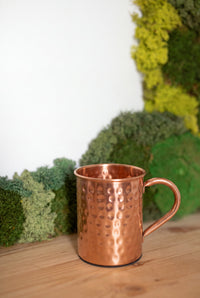 Kopero Copper Mug Hammered in front of a moss painting on a pine shelf
