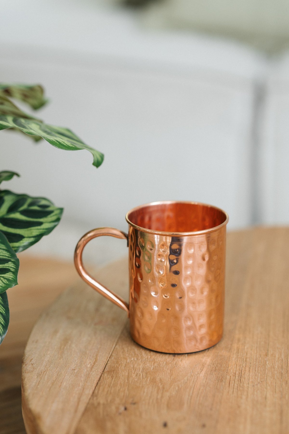 Kopero Copper Mug Hammered, on a round wooden table in front of a sofa