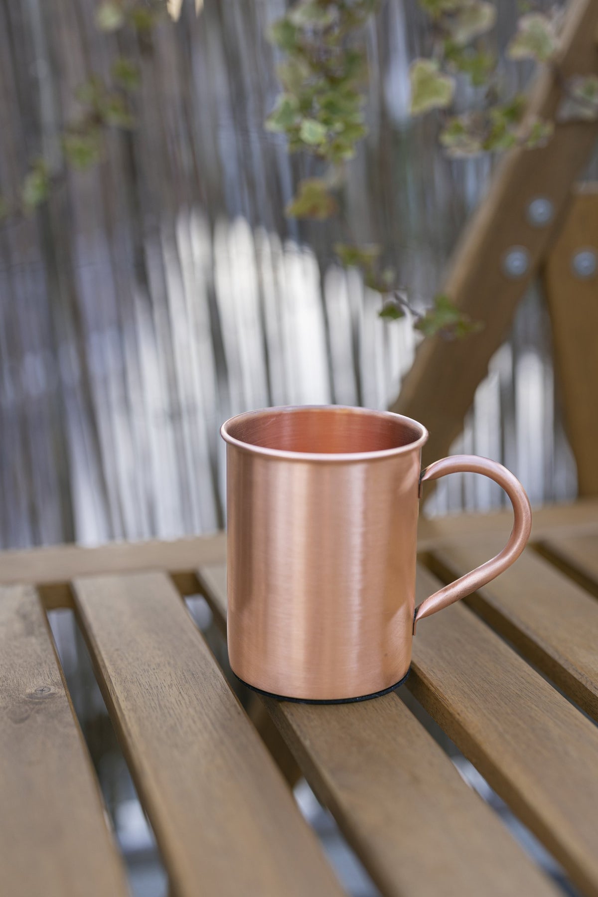 Kopero Copper Mug Smooth 400 ml on a wooden garden bench