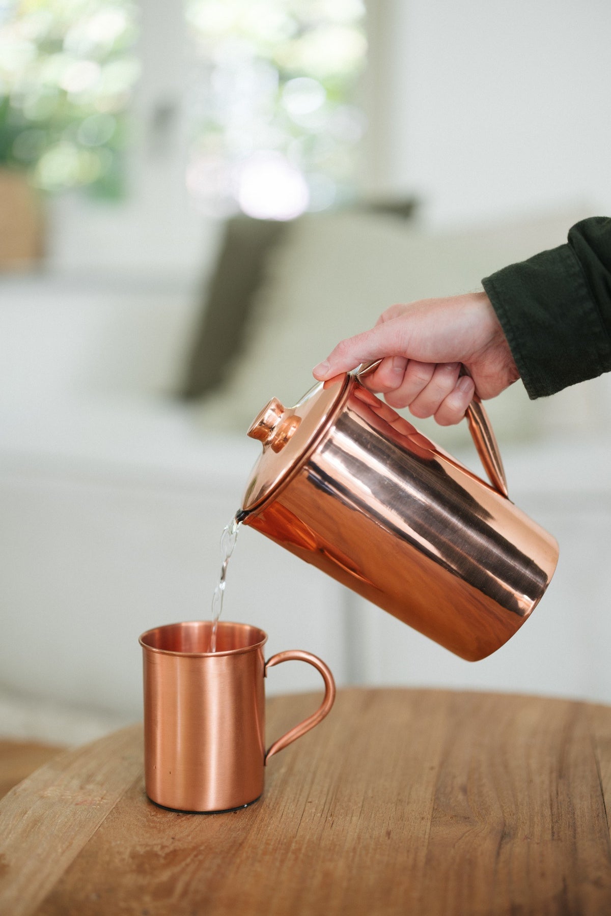 Kopero Copper Mug Smooth, while water is poured in from a copper jug