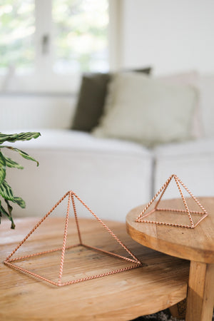 Kopero Copper Pyramid Energizer Twisted, the small and the large pyramid side by side on two wooden tables
