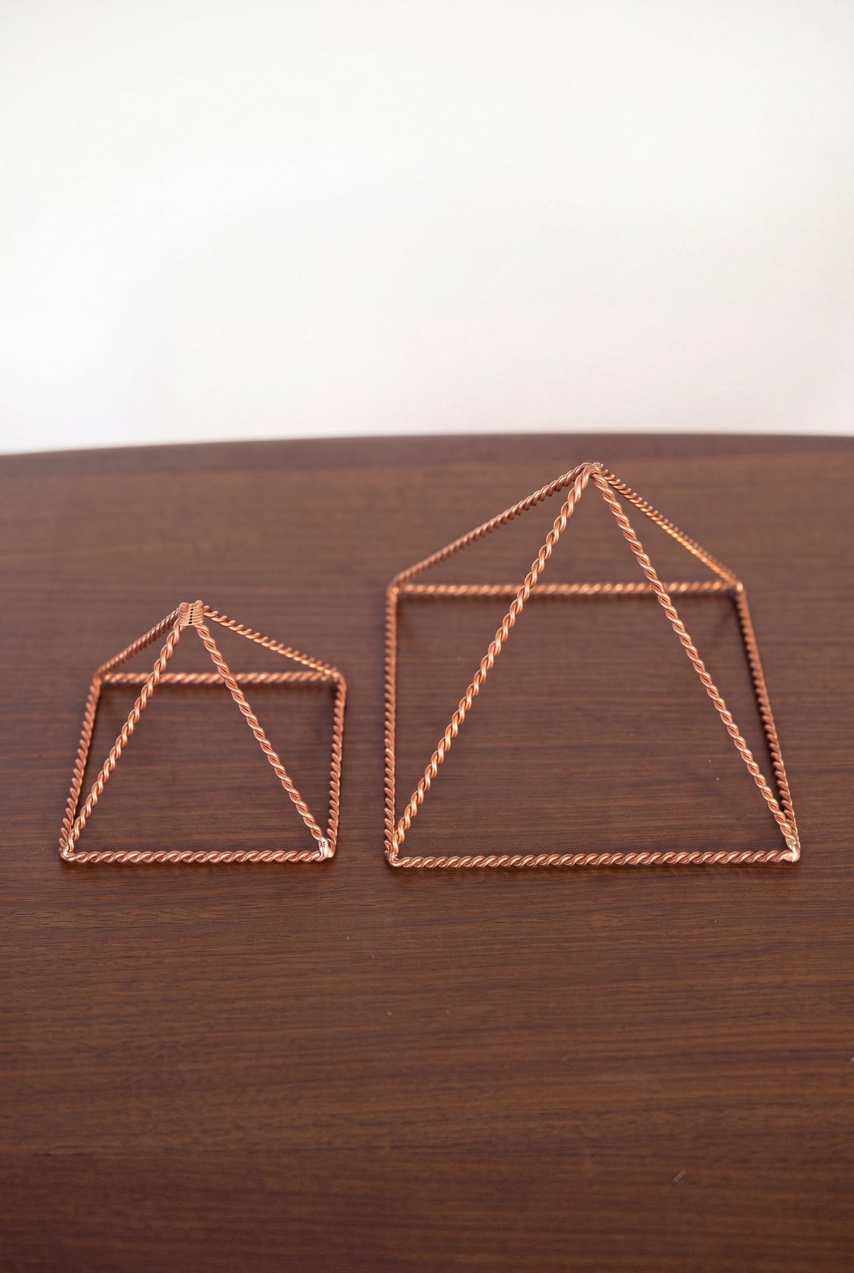 Kopero Copper Pyramid Energizer Twisted, both sizes side by side on a wooden table