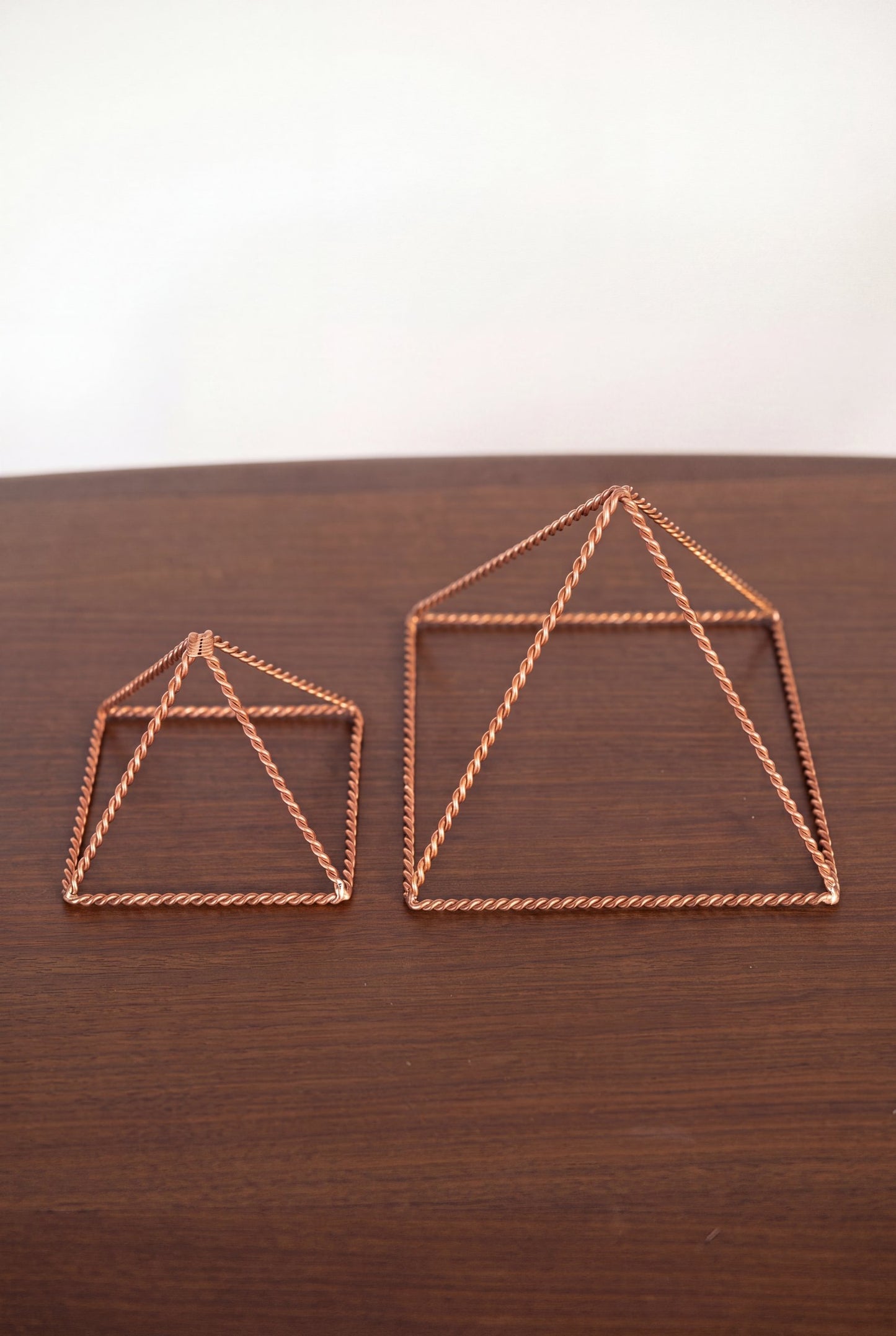 Kopero Copper Pyramid Energizer Twisted, both sizes side by side on a wooden table