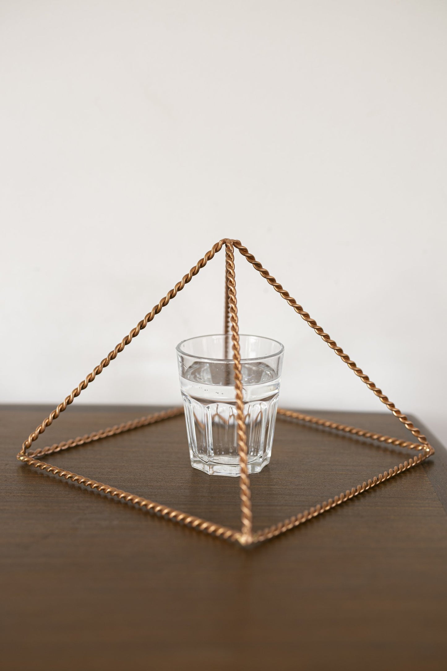 Kopero Copper Pyramid Energizer Twisted Large (23.56 cm) above a glass of water