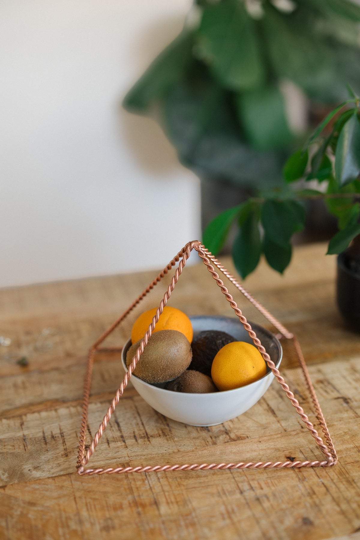 Kopero Copper Pyramid Energizer Twisted Large (23.56 cm), with a fruit bowl underneath