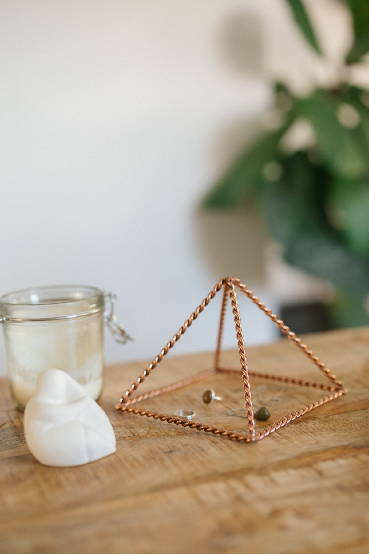 Kopero Copper Pyramid Energizer Twisted Small (14.56 cm), with jewellery underneath next to a candle jar and a figurine