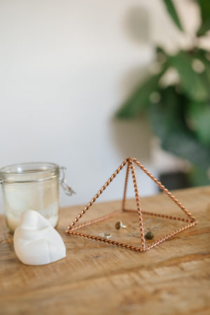 Kopero Copper Pyramid Energizer Twisted Small (14.56 cm), with jewellery underneath next to a candle jar and a figurine