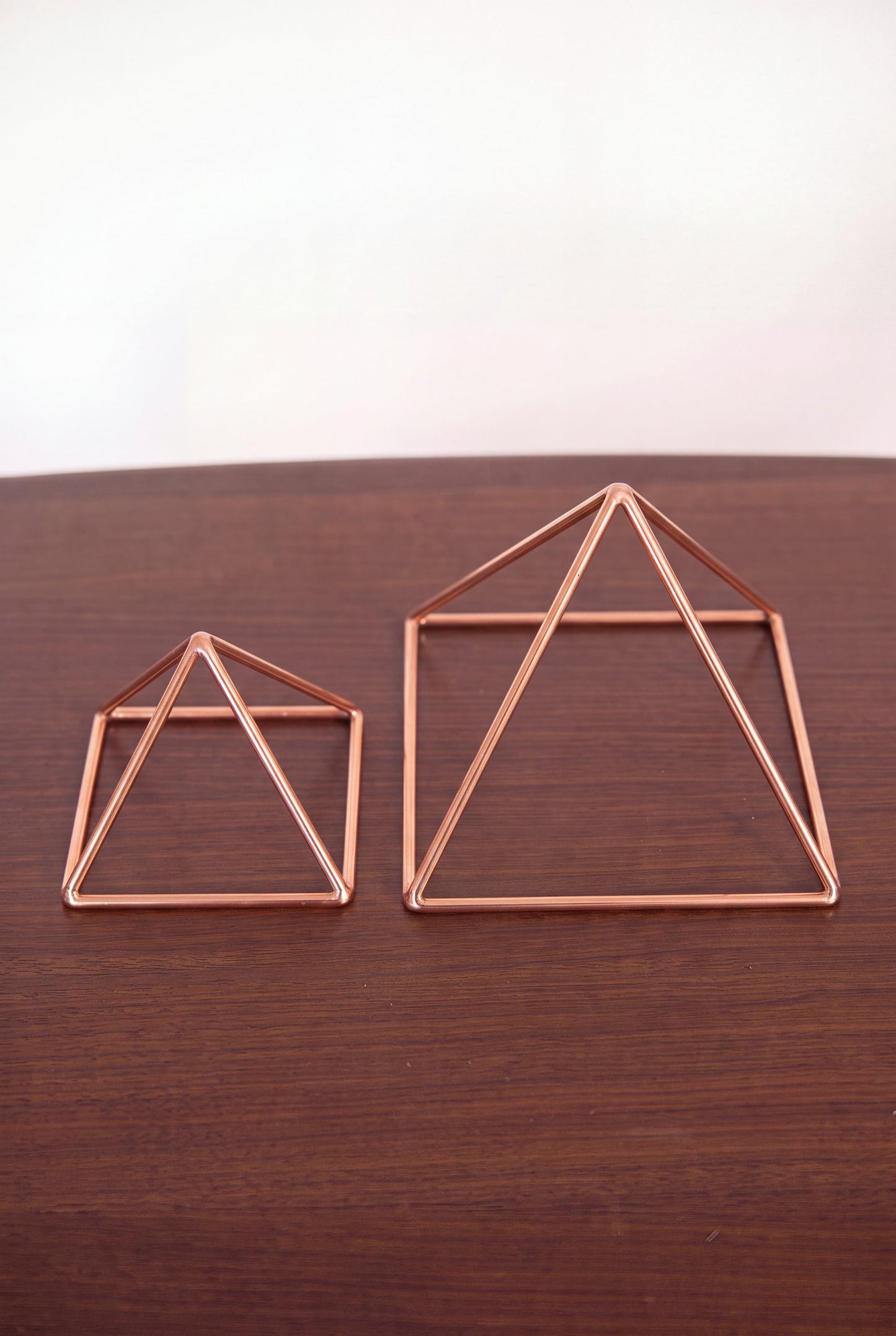 Kopero Copper Pyramid Energizer Smooth, both sizes side by side on a wooden table