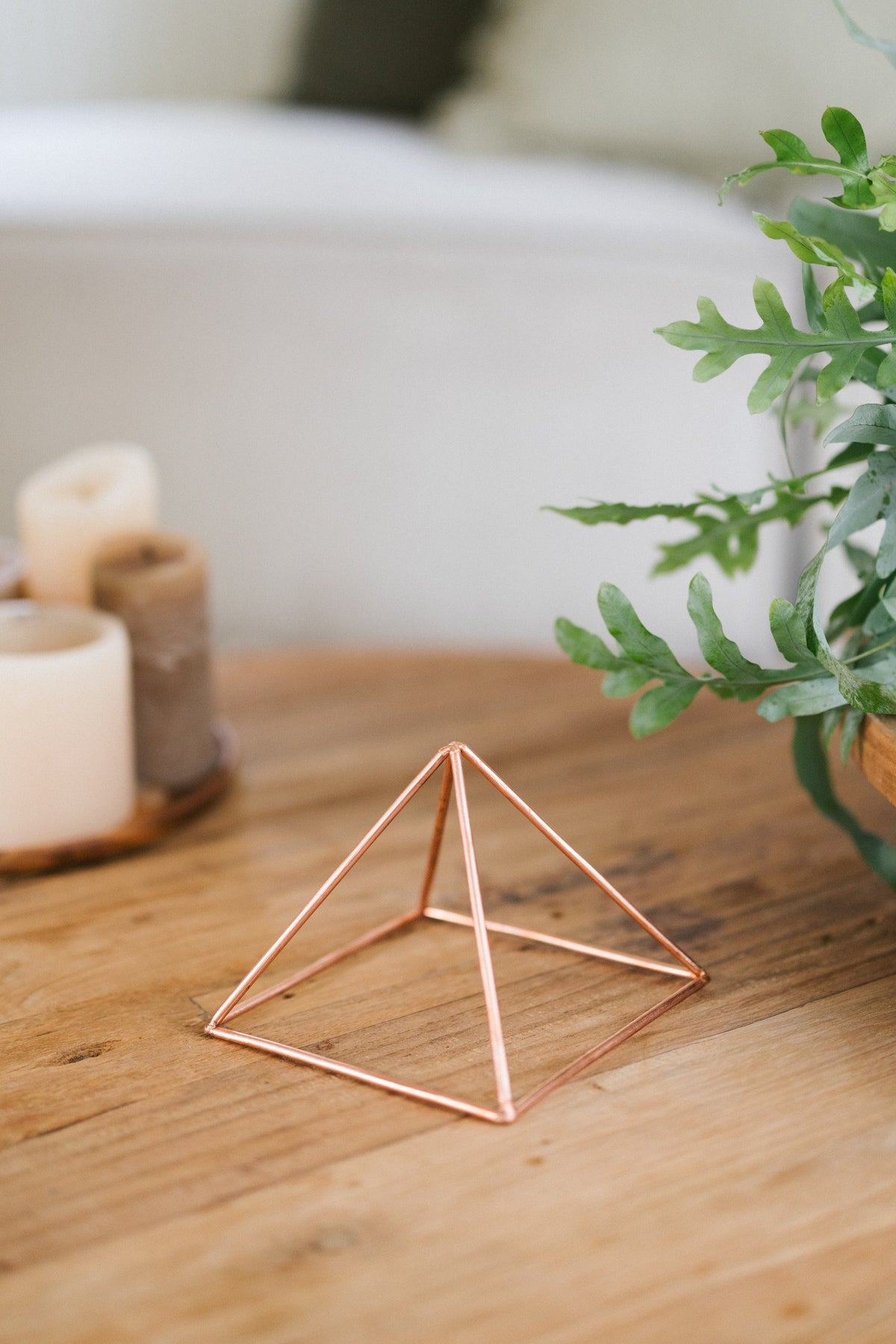Kopero Copper Pyramid Energizer Smooth Small (14.56 cm), on a wooden table next to candles