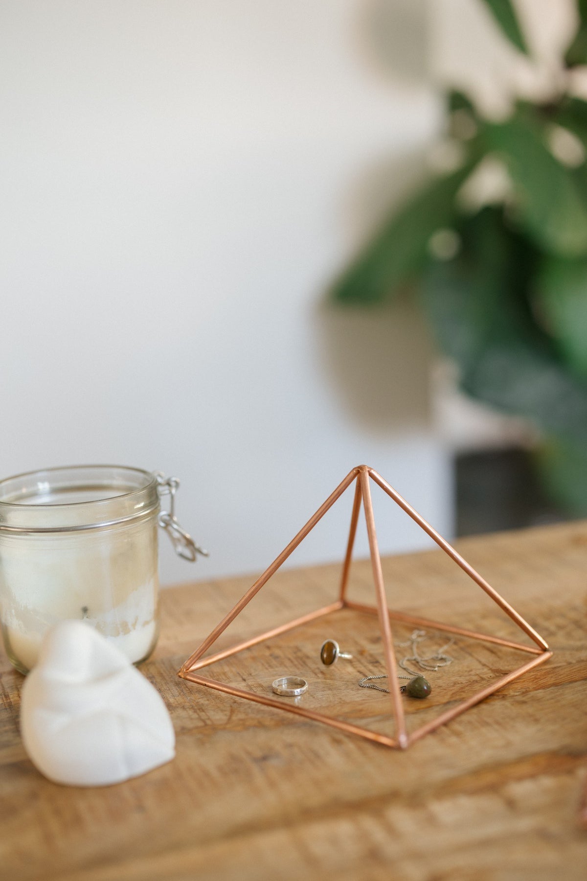 Kopero Copper Pyramid Energizer Smooth Small (14.56 cm), with jewellery underneath next to a candle jar and a figurine