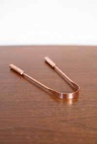 Kopero Copper Tongue Scraper made of pure copper on a wooden table