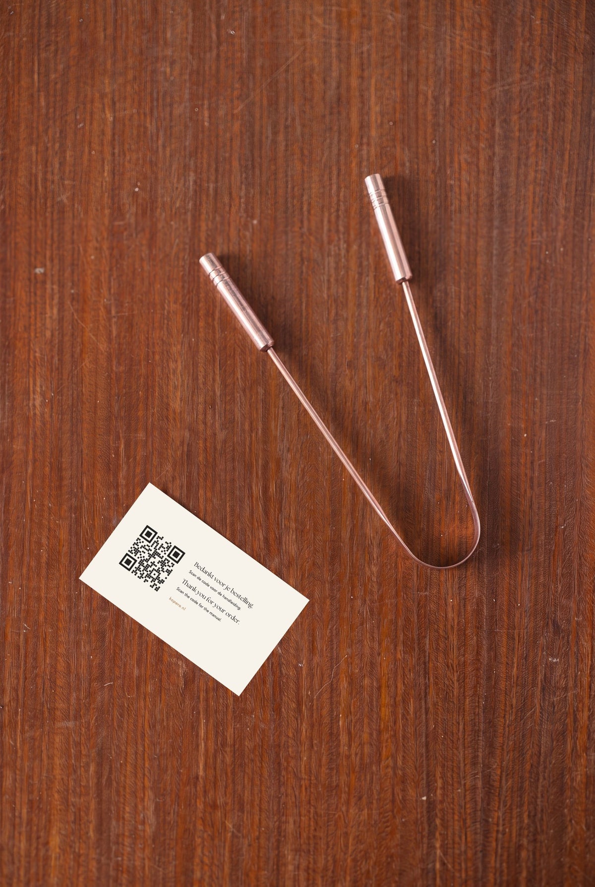 Kopero Copper Tongue Scraper from above on wood, with thank-you card