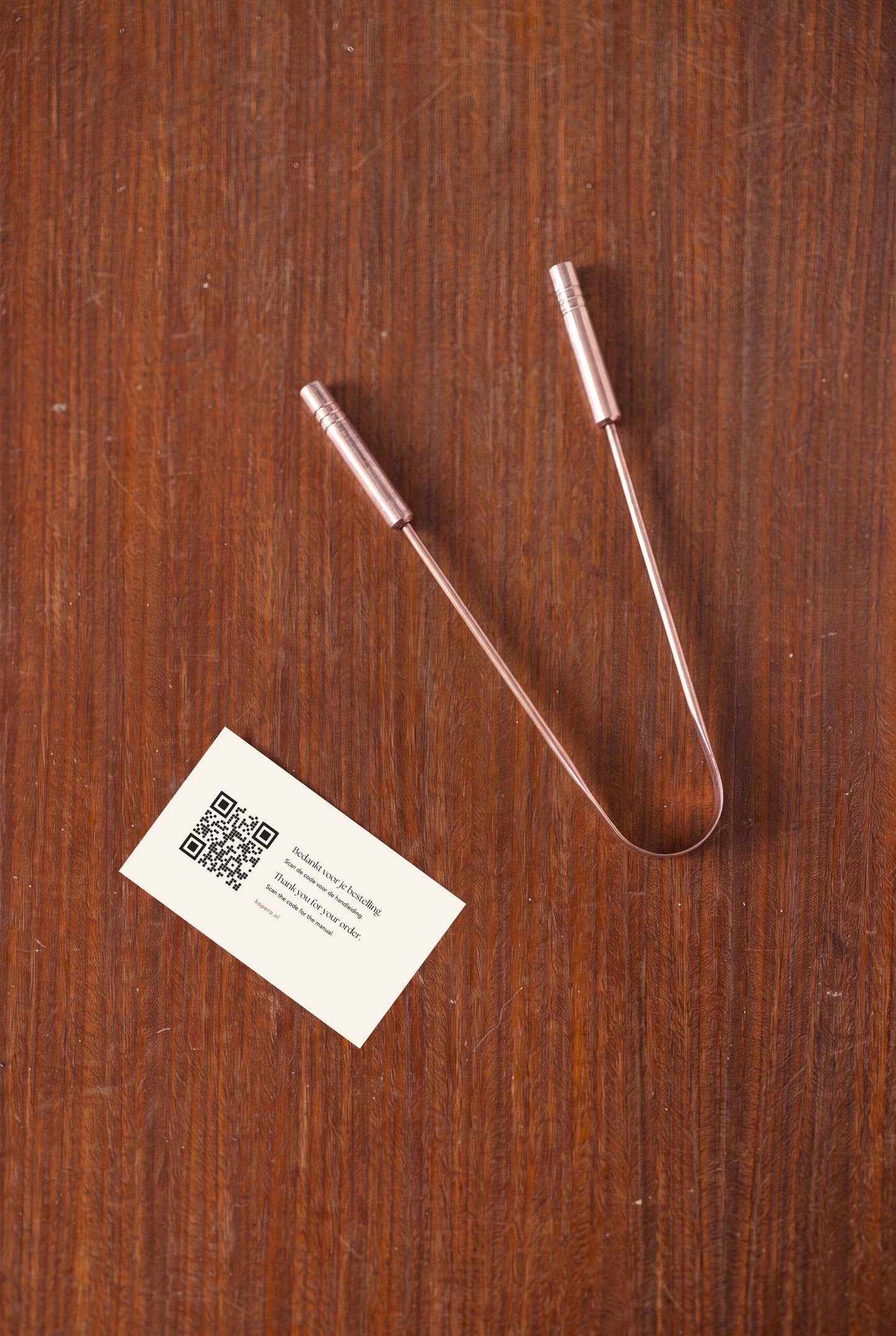 Kopero Copper Tongue Scraper from above on wood, with thank-you card