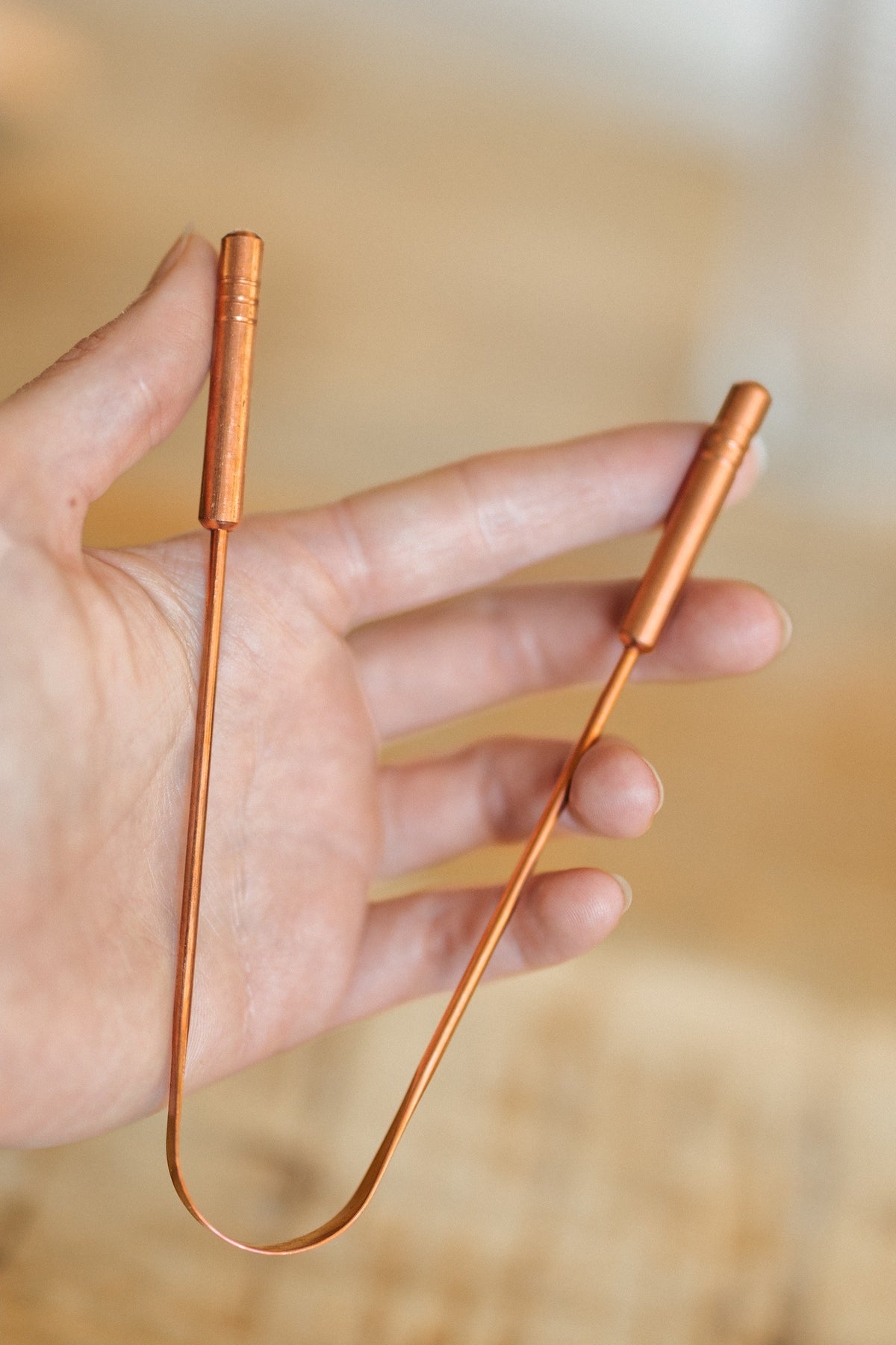 Kopero Copper Tongue Scraper, in an open hand, with both handles