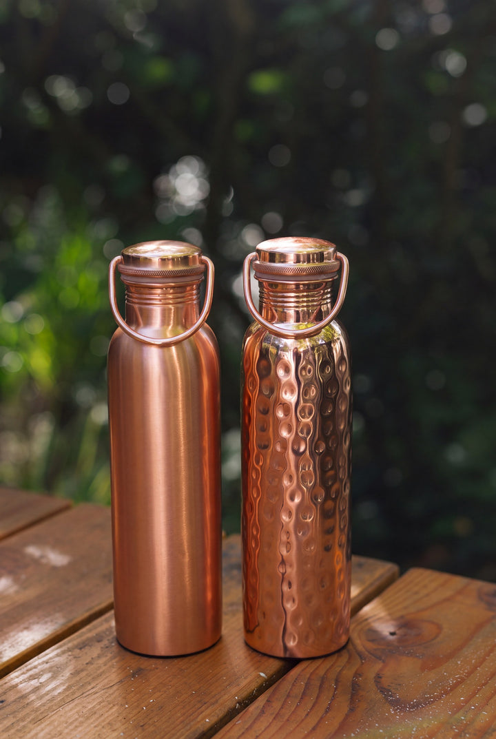 Kopero Copper Water Bottle, the smooth and the hammered bottle side by side on a wooden garden table