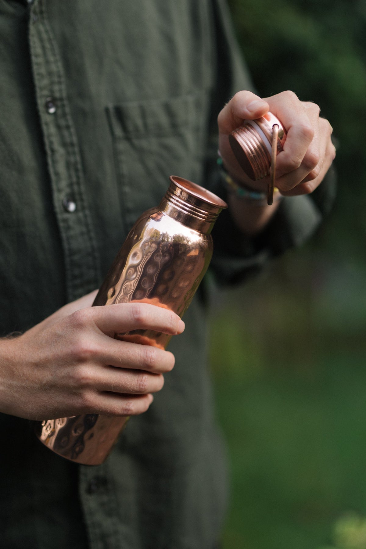 Kopero Copper Water Bottle Hammered, in a hand, while the cap is being unscrewed