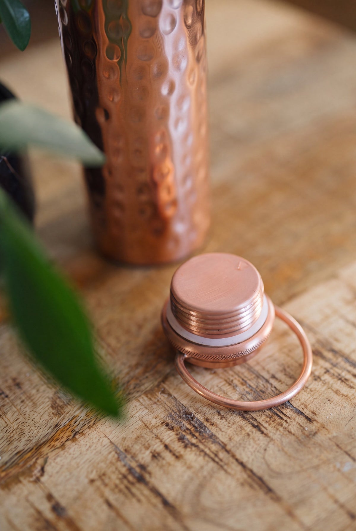 Kopero Copper Water Bottle Hammered, close-up of the loose cap with turning handle on a wooden table