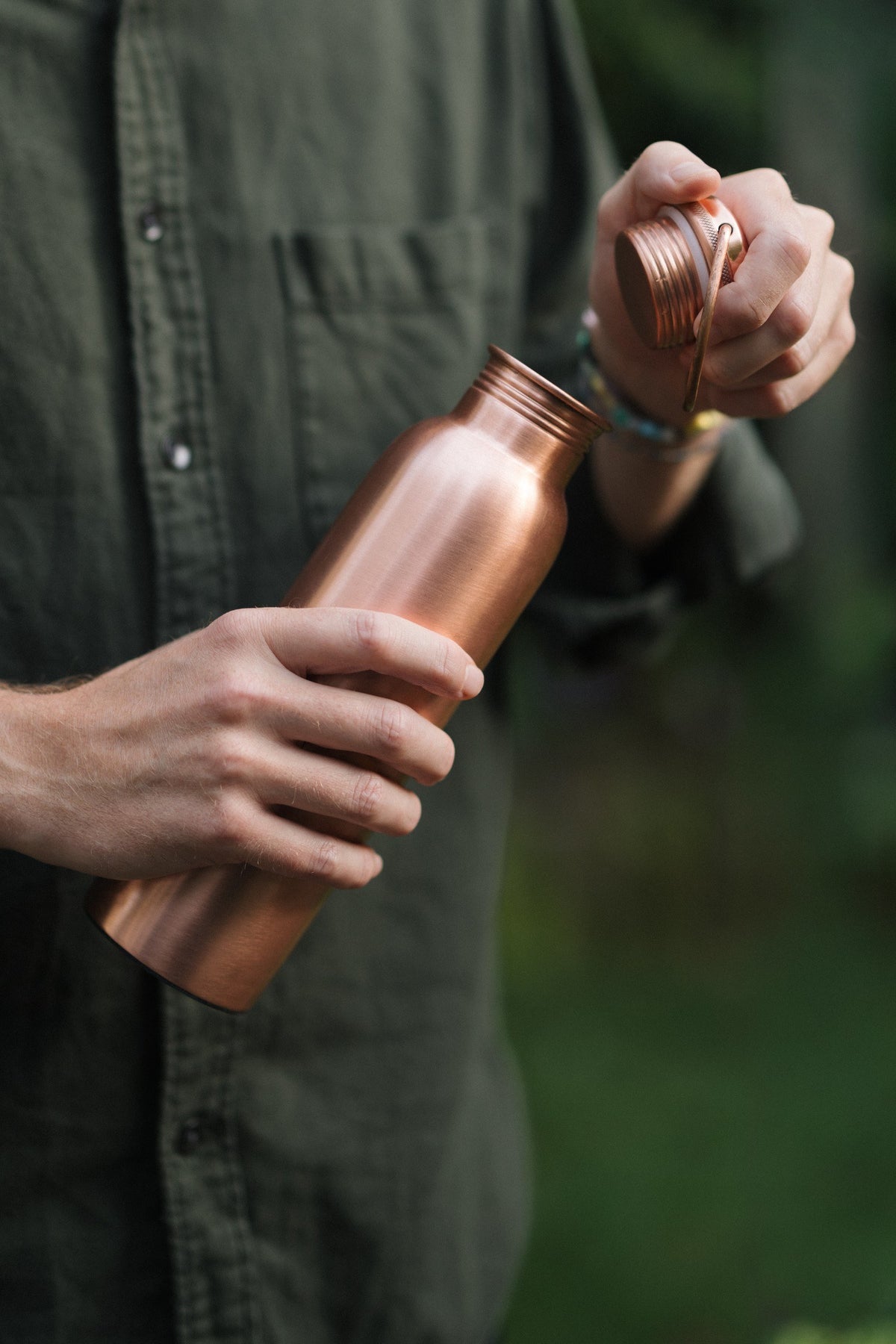Kopero Copper Water Bottle Smooth, in a hand, while the cap is being unscrewed